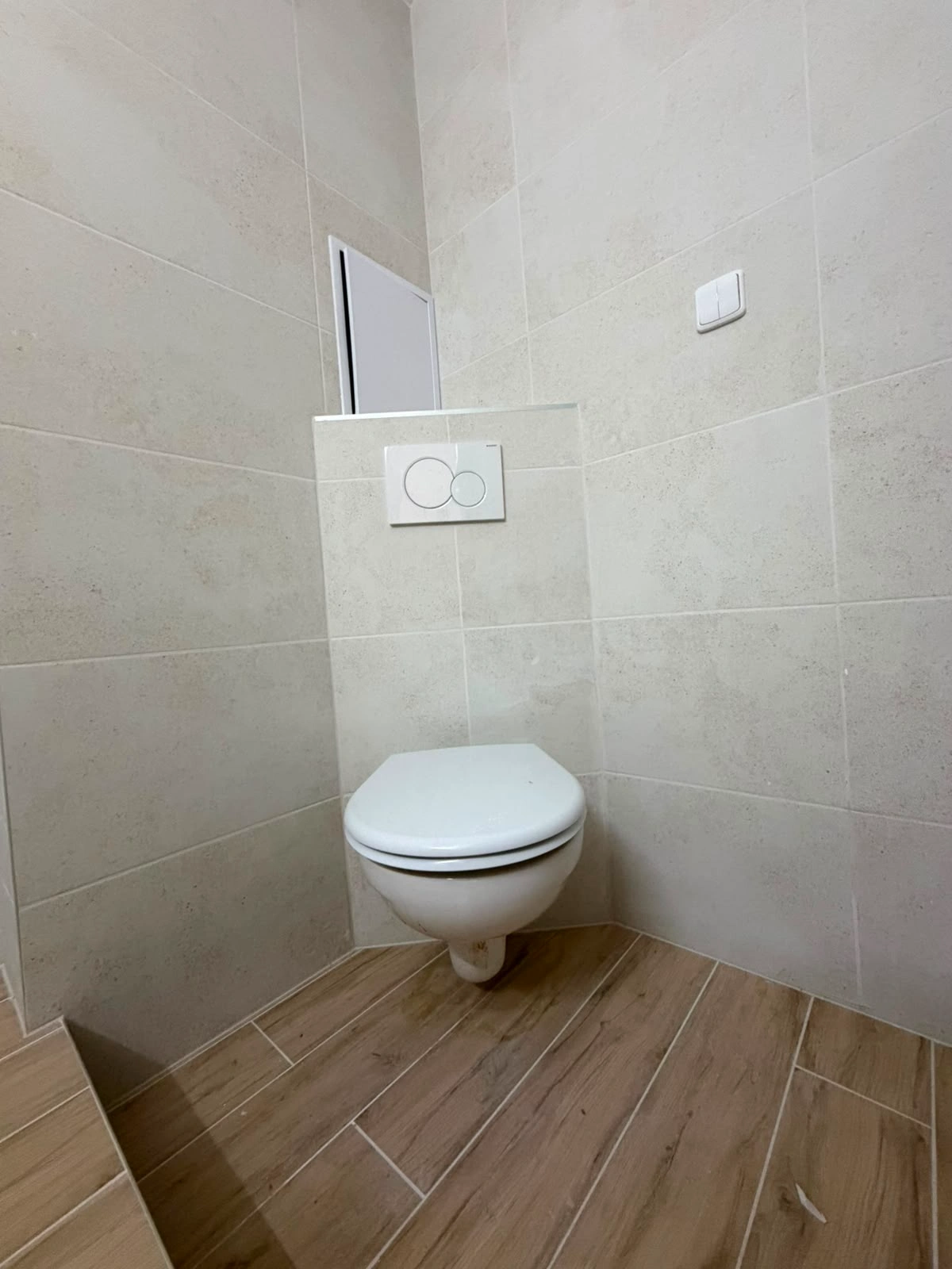 Rekonstrukce koupelny Ostrava – závěsné WC s tlačítkem a dřevodekorem dlažby